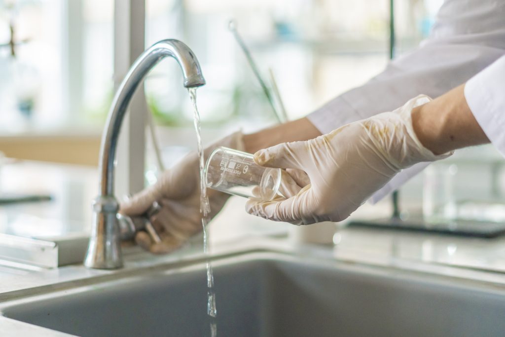 scientist wash beaker from poisonous acid after experiments