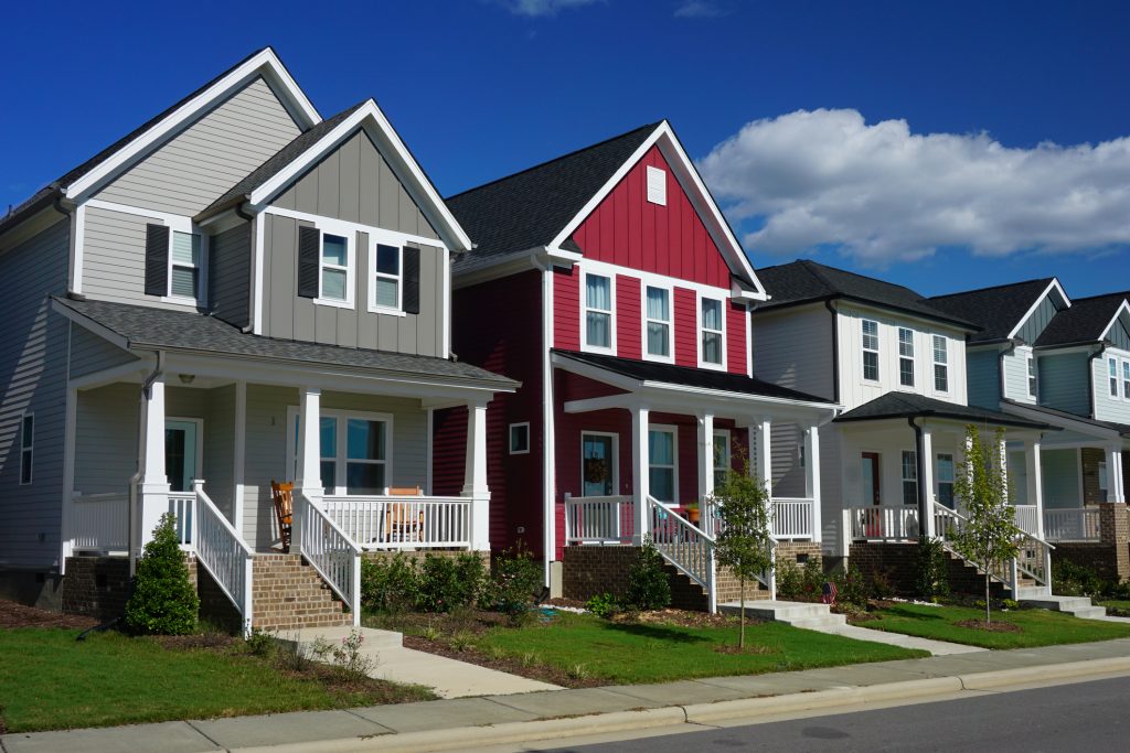 Street view of a row of houses. The front of each house has a porch, stairs and a sidewalk.